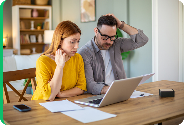 Bezorgd koppel dat naar een laptop kijkt thuis, terwijl ze hun energiefactuur of het capaciteitstarief analyseren.