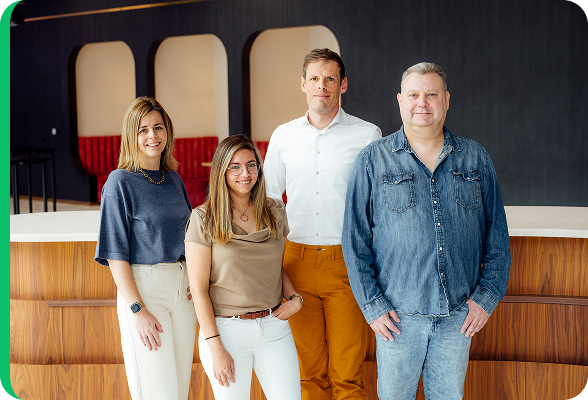 Team van vier experts, Kenneth Vansina, Melissa Vanhove, Eric Piette en Lynn Guillaume die samen poseren in een modern kantoor, als vertegenwoordiging van het merk Mijnenergie.be